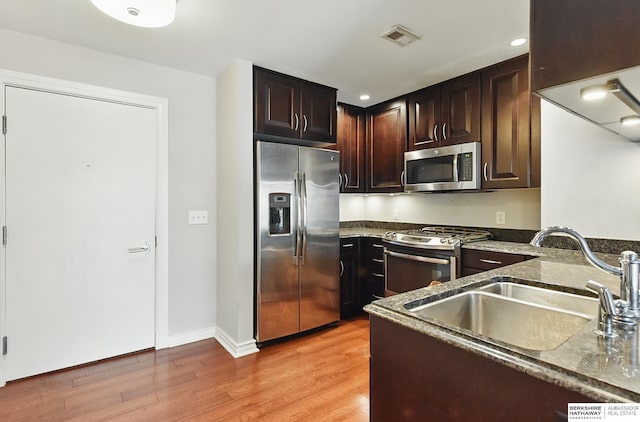 3200 Farnam Ct Unit 3409, Omaha, NE 68131 - kitchen with stainless steel appliances, a sink, light wood-style floors, dark stone countertops, and dark brown cabinetry