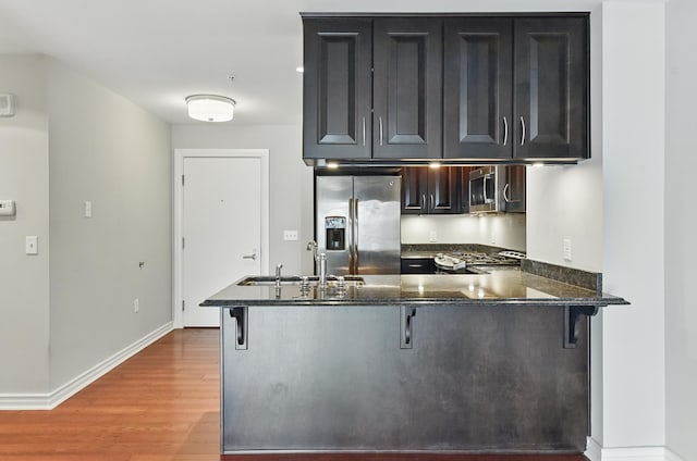 3200 Farnam Ct Unit 3409, Omaha, NE 68131 - kitchen featuring appliances with stainless steel finishes, a sink, light wood-type flooring, a breakfast bar area, and a peninsula