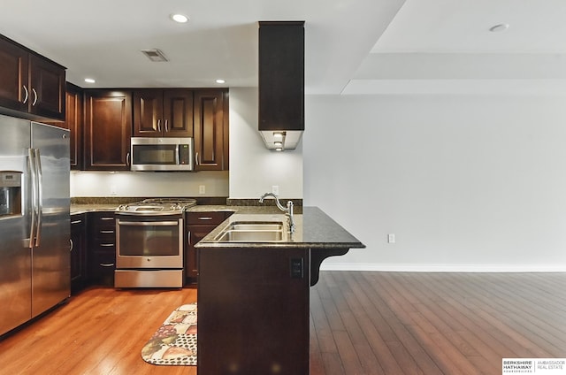 3200 Farnam Ct Unit 3409, Omaha, NE 68131 - kitchen with stainless steel appliances, a peninsula, a sink, a breakfast bar area, and light wood-style floors