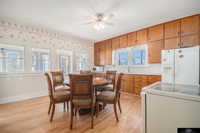 13602 S 36th St, Bellevue, NE 68123 - dining room featuring light wood-style flooring, wallpapered walls, a ceiling fan, and baseboards