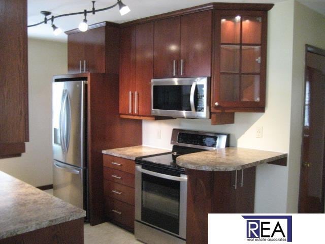 4521 A St, Omaha, NE 68106 - kitchen featuring stainless steel appliances, glass insert cabinets, track lighting, and light countertops