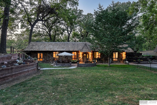 4128 State St, Omaha, NE 68112 - rear view of property with stone siding, a lawn, and a vegetable garden