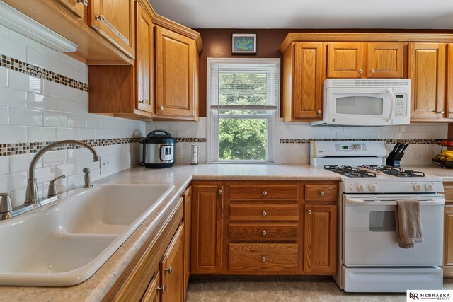 5042 Corby St, Omaha, NE 68104 - kitchen featuring white appliances, light countertops, brown cabinets, and tasteful backsplash