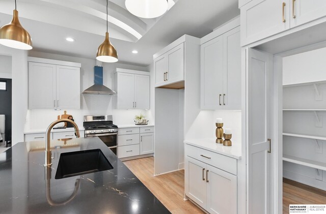 16951 Benjamin St, Bennington, NE 68007 - kitchen with wall chimney exhaust hood, stainless steel range with gas stovetop, light wood finished floors, recessed lighting, and hanging light fixtures