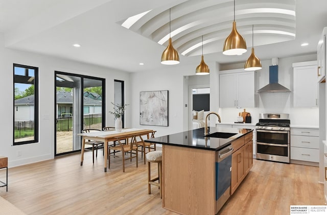 16951 Benjamin St, Bennington, NE 68007 - kitchen with stainless steel appliances, wall chimney range hood, light wood-style floors, an island with sink, and recessed lighting