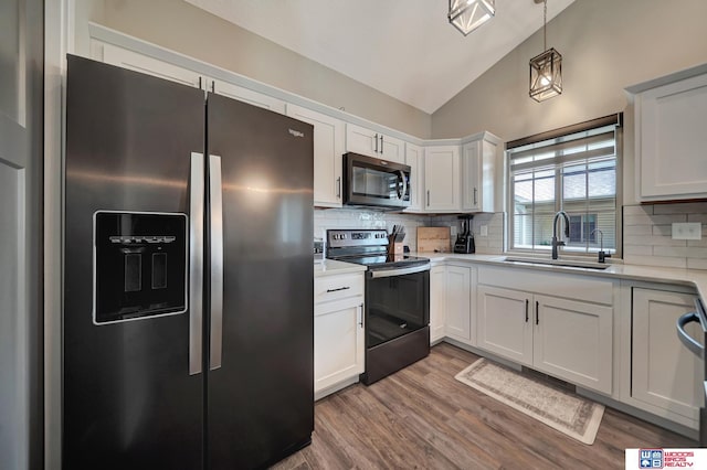 8178 Regent Dr, Lincoln, NE 68507 - kitchen featuring stainless steel appliances, vaulted ceiling, light countertops, wood finished floors, and decorative backsplash