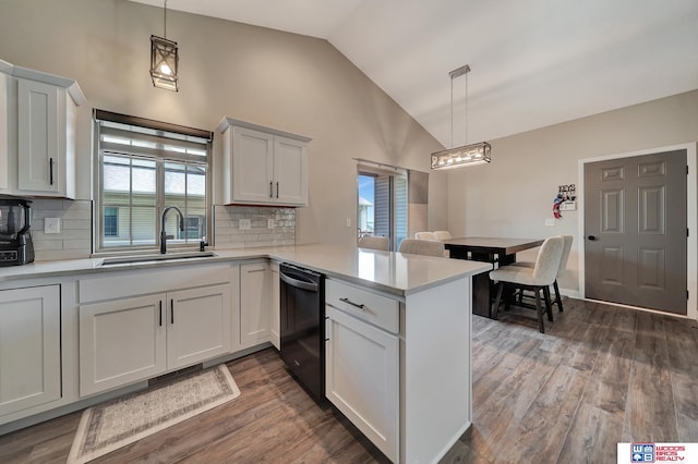 8178 Regent Dr, Lincoln, NE 68507 - kitchen with black dishwasher, vaulted ceiling, a peninsula, light countertops, and wood finished floors
