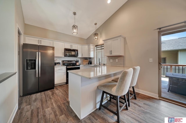 8178 Regent Dr, Lincoln, NE 68507 - kitchen featuring appliances with stainless steel finishes, a peninsula, tasteful backsplash, light countertops, and a breakfast bar area