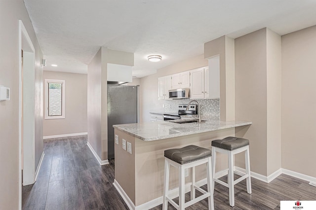 7420 S St S Unit 13, Lincoln, NE 68506 - kitchen with appliances with stainless steel finishes, dark wood-style floors, a peninsula, and light stone countertops