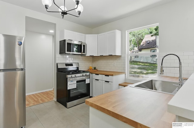 3410 U St, Omaha, NE 68107 - kitchen featuring stainless steel appliances, butcher block counters, white cabinetry, a chandelier, and light tile patterned floors