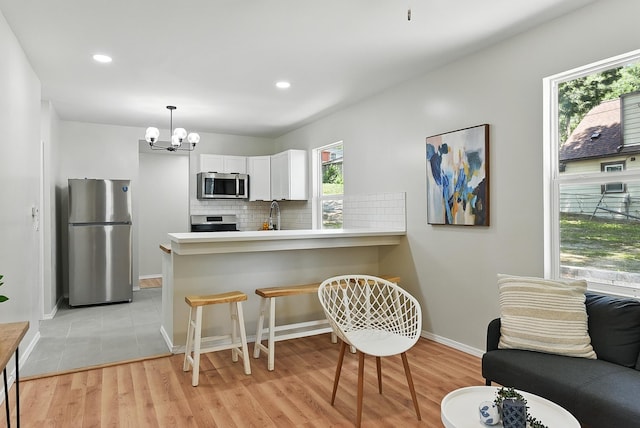 3410 U St, Omaha, NE 68107 - kitchen featuring appliances with stainless steel finishes, white cabinetry, tasteful backsplash, a chandelier, and light countertops