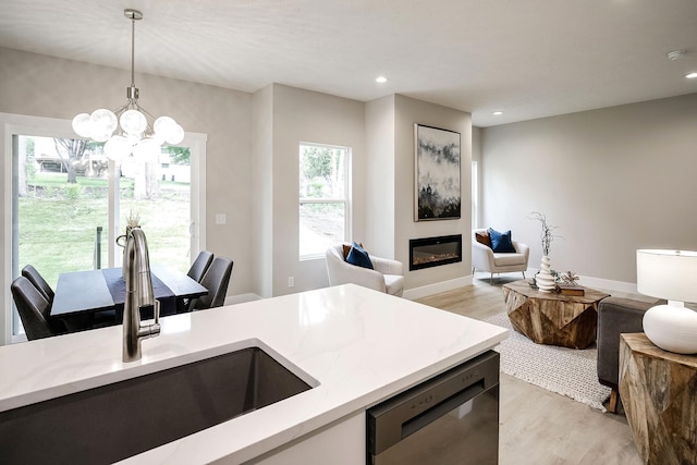 5445 S 51st St, Omaha, NE 68117 - kitchen featuring stainless steel dishwasher, light wood-style floors, hanging light fixtures, light stone countertops, and open floor plan