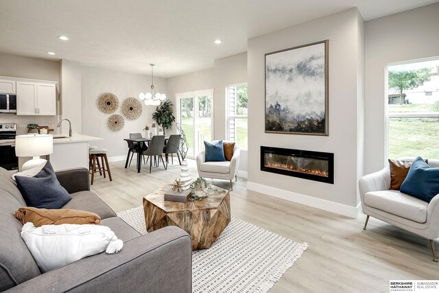 5445 S 51st St, Omaha, NE 68117 - living room with a chandelier, recessed lighting, light wood-type flooring, healthy amount of natural light, and a glass covered fireplace