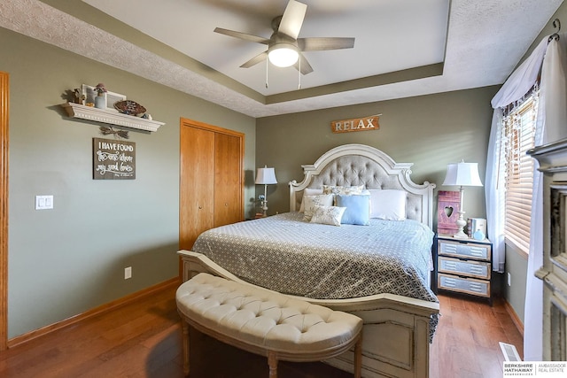 6705 Hillcrest Ln, La Vista, NE 68128 - bedroom featuring a tray ceiling, wood finished floors, a closet, and ceiling fan