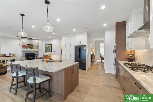 5850 Country Squire Plz, Omaha, NE 68152 - kitchen featuring appliances with stainless steel finishes, open floor plan, wall chimney range hood, a fireplace, and light stone countertops