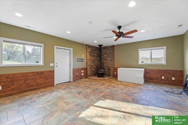 5850 Country Squire Plz, Omaha, NE 68152 - unfurnished living room featuring a wood stove, plenty of natural light, recessed lighting, wainscoting, and a ceiling fan
