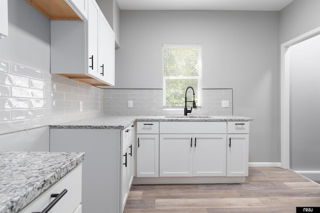 1204 S 27th St, Omaha, NE 68105 - kitchen with light wood-style floors, white cabinetry, and light stone countertops
