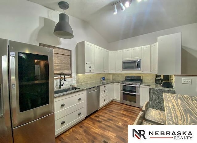 19003 Morrissey Cir, Omaha, NE 68022 - kitchen featuring appliances with stainless steel finishes, vaulted ceiling, light stone countertops, decorative backsplash, and dark wood finished floors