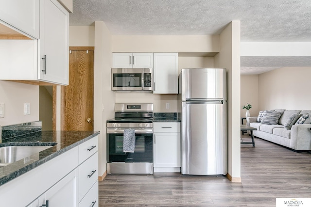 5424 Canterbury Ln Unit 5424, Lincoln, NE 68512 - kitchen featuring appliances with stainless steel finishes, dark wood-style flooring, a textured ceiling, white cabinets, and dark stone counters