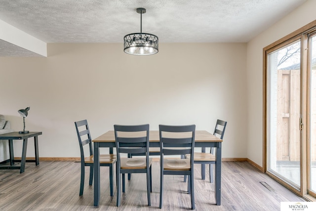 5424 Canterbury Ln Unit 5424, Lincoln, NE 68512 - dining room featuring light wood-type flooring, a textured ceiling, and a chandelier