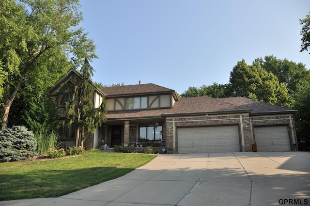 1017 N 129th Cir, Omaha, NE 68154 - tudor house with a garage, concrete driveway, a front yard, and brick siding