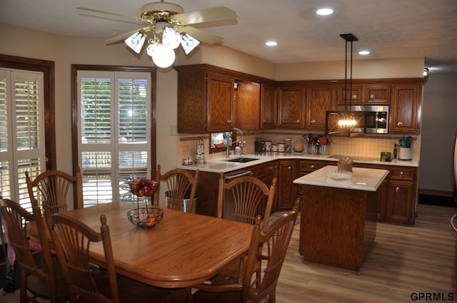 1017 N 129th Cir, Omaha, NE 68154 - kitchen with a ceiling fan, light countertops, light wood-type flooring, backsplash, and a center island