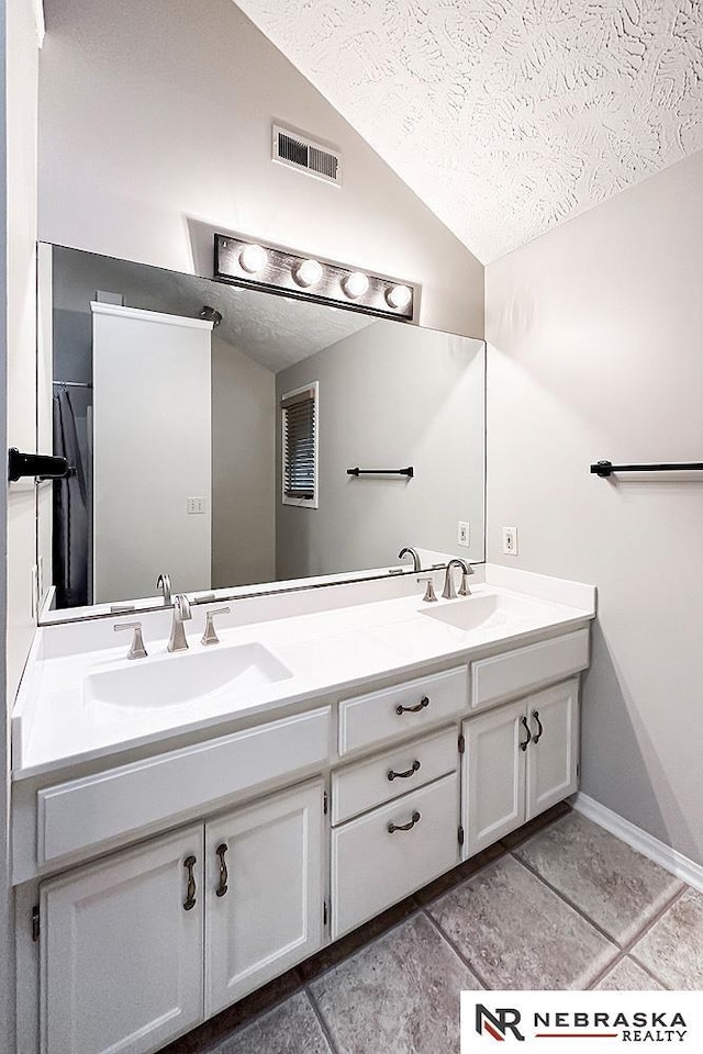 1425 S 158th Cir, Omaha, NE 68130 - full bath featuring a textured ceiling, double vanity, vaulted ceiling, and tile patterned floors