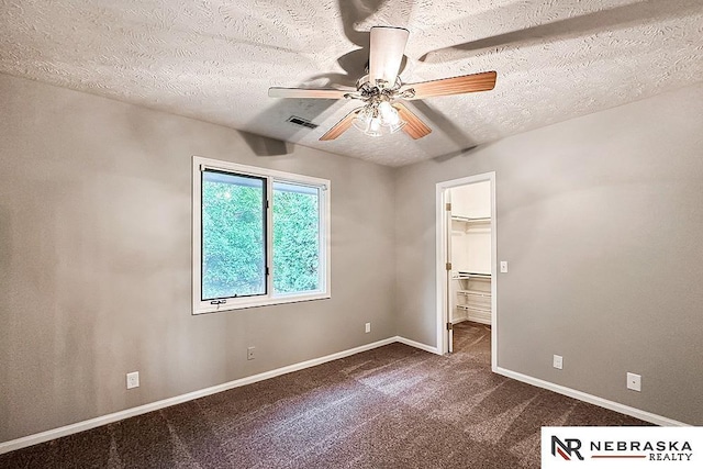 1425 S 158th Cir, Omaha, NE 68130 - unfurnished bedroom featuring dark colored carpet, a textured ceiling, a spacious closet, and ceiling fan