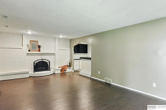 7504 S 46th Ave, Omaha, NE 68157 - unfurnished living room featuring dark wood-type flooring, a brick fireplace, and arched walkways