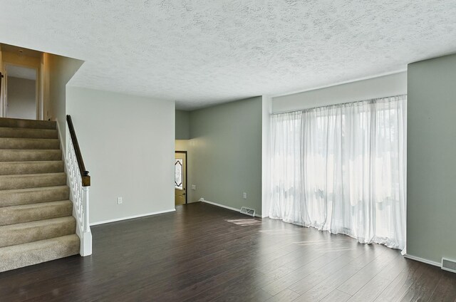 7504 S 46th Ave, Omaha, NE 68157 - unfurnished living room featuring dark wood-style floors, stairway, and a textured ceiling