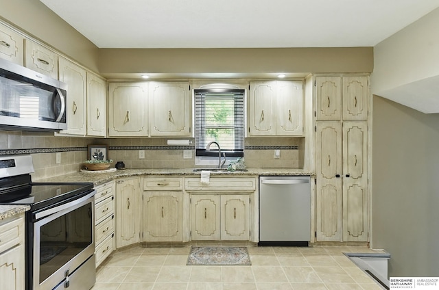 7504 S 46th Ave, Omaha, NE 68157 - kitchen with stainless steel appliances, decorative backsplash, light stone counters, and light tile patterned flooring