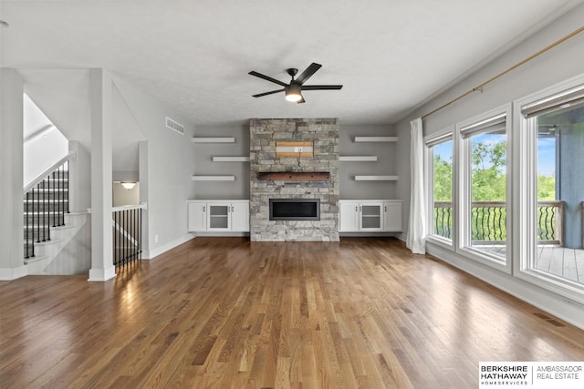 19014 Pratt Cir, Elkhorn, NE 68022 - unfurnished living room featuring wood finished floors, a ceiling fan, stairs, and a stone fireplace
