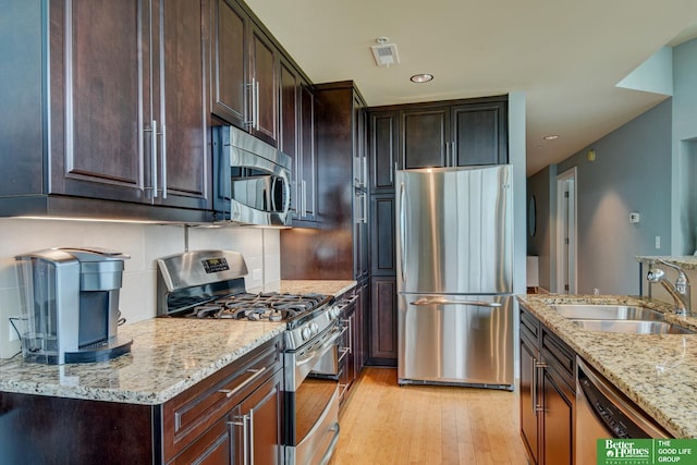 444 Riverfront Plz Unit 501, Omaha, NE 68102 - kitchen featuring appliances with stainless steel finishes, light wood finished floors, light stone counters, dark brown cabinets, and recessed lighting