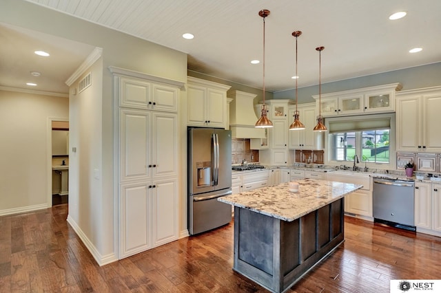 820 N 100th St, Lincoln, NE 68527 - kitchen featuring appliances with stainless steel finishes, glass insert cabinets, custom range hood, light stone counters, and decorative light fixtures
