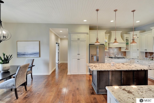 820 N 100th St, Lincoln, NE 68527 - kitchen with custom range hood, stainless steel refrigerator with ice dispenser, hardwood / wood-style flooring, a center island, and glass insert cabinets