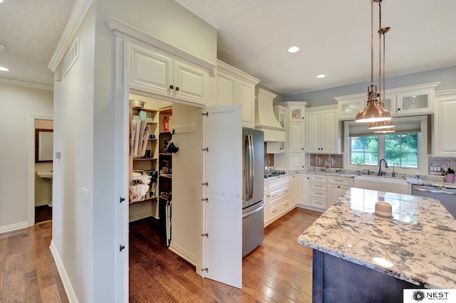 820 N 100th St, Lincoln, NE 68527 - kitchen featuring premium range hood, light wood finished floors, appliances with stainless steel finishes, light stone countertops, and recessed lighting