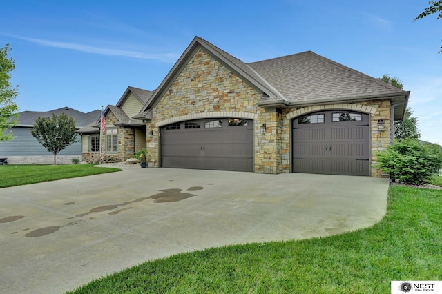 820 N 100th St, Lincoln, NE 68527 - french country home with stone siding, an attached garage, driveway, roof with shingles, and a front yard