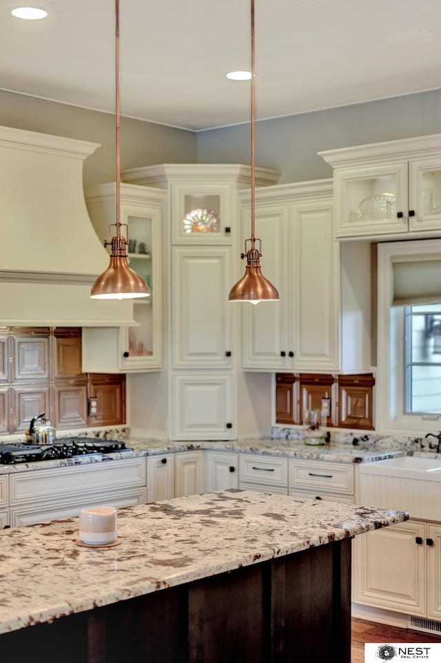 820 N 100th St, Lincoln, NE 68527 - kitchen featuring hanging light fixtures, glass insert cabinets, light stone countertops, and recessed lighting