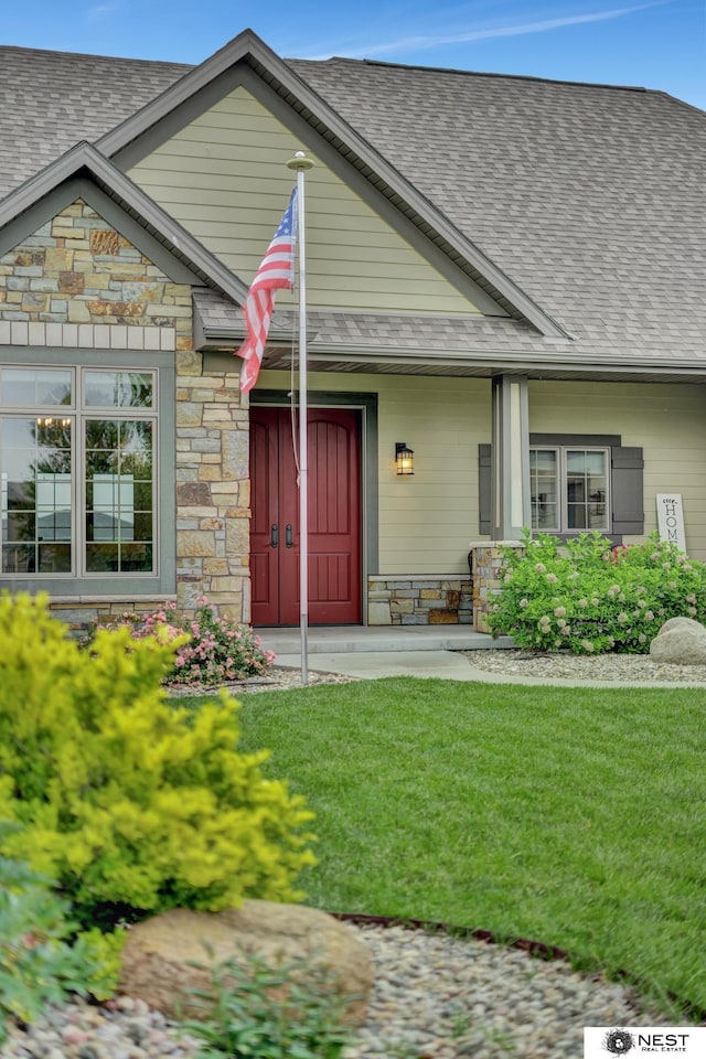 820 N 100th St, Lincoln, NE 68527 - view of front facade with stone siding, roof with shingles, and a front lawn