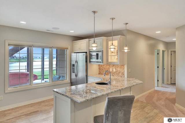 820 N 100th St, Lincoln, NE 68527 - kitchen with stainless steel appliances, a kitchen bar, light stone countertops, a peninsula, and glass insert cabinets