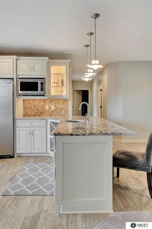 820 N 100th St, Lincoln, NE 68527 - kitchen with stainless steel appliances, light stone countertops, light wood finished floors, white cabinets, and tasteful backsplash