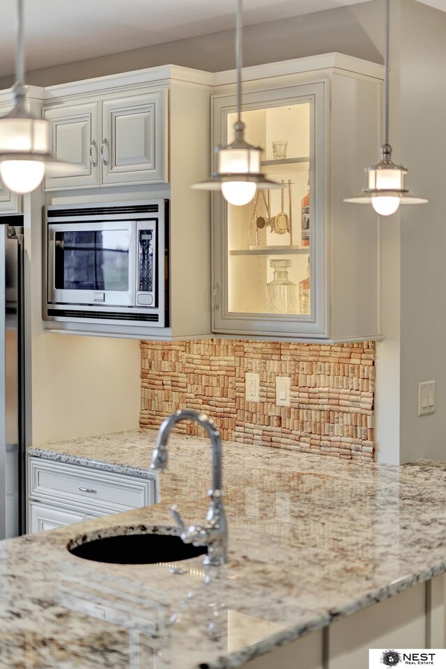 820 N 100th St, Lincoln, NE 68527 - kitchen with stainless steel microwave, decorative backsplash, decorative light fixtures, light stone countertops, and refrigerator