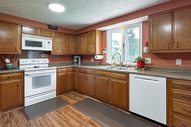 1817 Holling Dr, Omaha, NE 68144 - kitchen featuring white appliances, light wood-style floors, brown cabinetry, and a textured ceiling