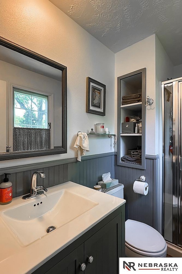 1817 Holling Dr, Omaha, NE 68144 - full bathroom featuring a shower stall, a wainscoted wall, vanity, and a textured ceiling