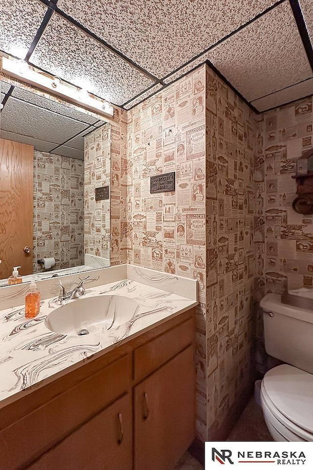 1817 Holling Dr, Omaha, NE 68144 - bathroom featuring wallpapered walls, vanity, and a drop ceiling