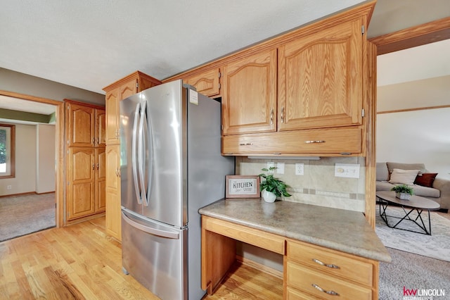 4630 Eagle Ridge Rd, Lincoln, NE 68516 - kitchen with freestanding refrigerator, light wood-style flooring, backsplash, built in desk, and light countertops