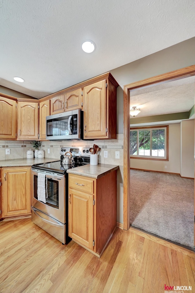 4630 Eagle Ridge Rd, Lincoln, NE 68516 - kitchen with appliances with stainless steel finishes, backsplash, light countertops, a textured ceiling, and light wood-type flooring