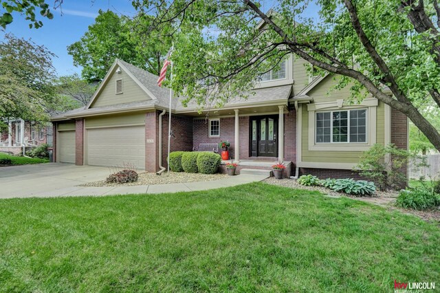 4630 Eagle Ridge Rd, Lincoln, NE 68516 - view of front facade with a garage, a front yard, concrete driveway, brick siding, and covered porch