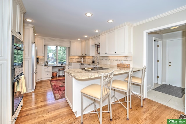 9706 Ascot Dr, Omaha, NE 68114 - kitchen with a peninsula, light wood finished floors, tasteful backsplash, recessed lighting, and ornamental molding