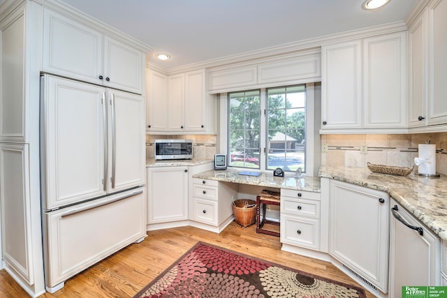 9706 Ascot Dr, Omaha, NE 68114 - kitchen featuring paneled refrigerator, stainless steel microwave, light wood-style flooring, white cabinetry, and decorative backsplash